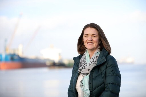 Niamh Kenny, Chair of REnewableNI offshore wind wg standing with Belfast docks in the blurred background