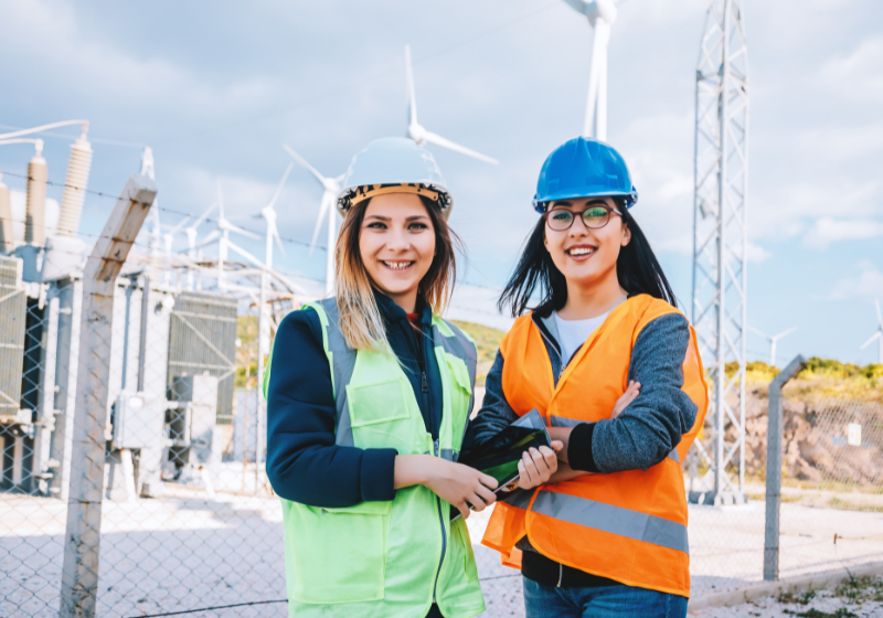 two women in hard hats and high vis in front of future and energy storage
